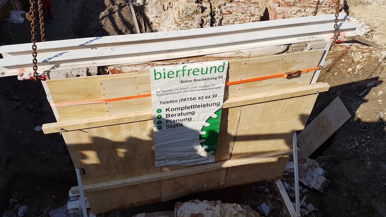 Mit bierfreund-Banner gesicherte Mauerscheibe wird am Kran transportiert